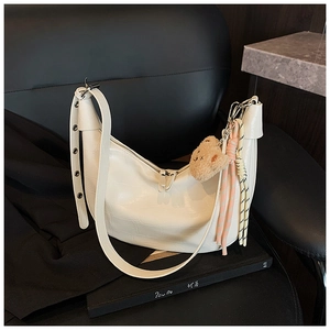 Detail of white crocodile embossed dumpling bag with a cute plush bear pendant accessory