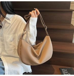 Close-up of a taupe half-moon leather shoulder bag with lychee texture and adjustable strap