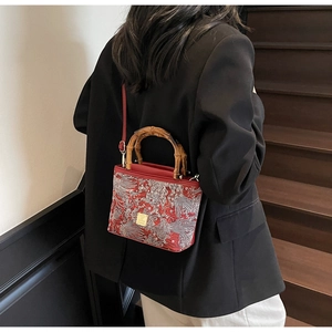 Detailed embroidery of white dragon on a red Chinese-style bamboo handle bucket bag