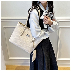 Detail of herringbone texture on beige tote bag and matching mini pouch accessory