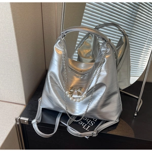 Detail der gesteppten Metallic-Tasche mit goldener Schleife und großen Perlenanhängern