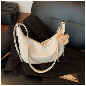 White croc-effect crescent bag with eyelet strap and plush bear charm detail