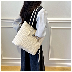 Detail of cream white tote bag featuring herringbone texture and mini coin purse accessory