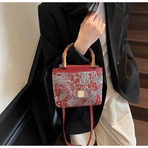 Macro shot of red embroidery bag with bamboo handle and vintage floral patterns