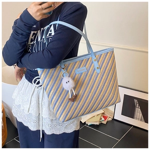 Détail du sac cabas rayé tissé main avec poignées en cuir bleu et breloque peluche