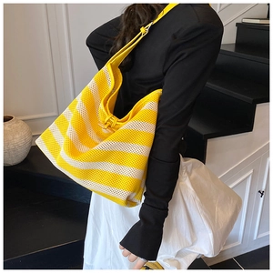 Detail of yellow and white striped knit mesh tote bag featuring a wooden button closure