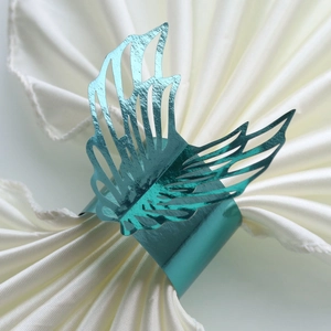 Macro detail of teal peacock blue angel wing napkin ring with intricate hollowed-out texture