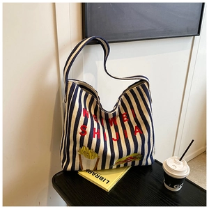 Détail d'un cabas en toile à rayures bleues avec lettres brodées et écussons