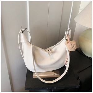Detail of white crocodile texture hobo bag with a cute brown bear charm and silver zipper