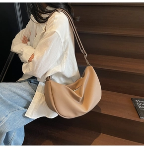 Close-up of light brown lychee grain leather hobo bag worn by model on wooden stairs