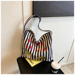 Détail du cabas en toile à rayures bleues avec broderie rouge et motif palmier