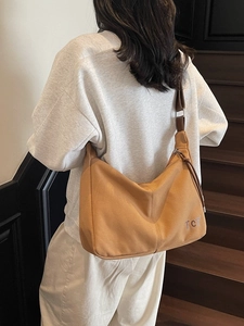 Retro Camel Hobo-Tasche mit TCT-Logo auf Holztreppen für einen minimalistischen Look