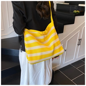 Detail of yellow and white striped mesh tote bag with wooden olive button closure