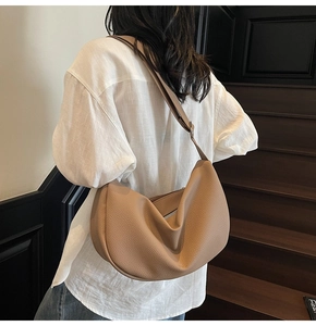 Detail view of khaki pebbled leather shoulder bag with crescent shape and silver zipper