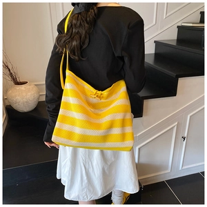 Detail of striped knitted tote bag with wooden button closure on a shoulder strap