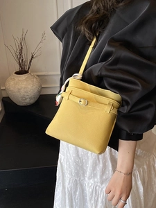 Sac seau jaune chic à texture litchi avec breloque fleur porté par un mannequin