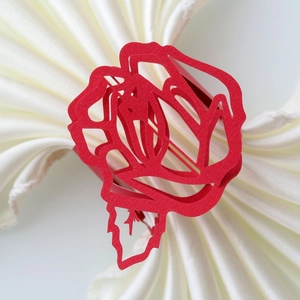 Detail view of red laser-cut rose napkin ring with intricate hollow floral patterns