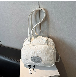 Détail du sac en toile blanche avec broderies florales 3D et plaque argentée