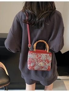 Chinese style red embroidered handbag with bamboo handle shown as a crossbody bag