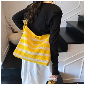 Detail of yellow and white striped knit tote bag featuring a wooden horn toggle closure