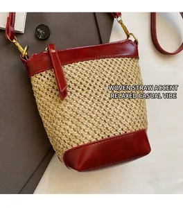 Detail of straw bucket bag featuring dark red leather trim and golden metal buckles