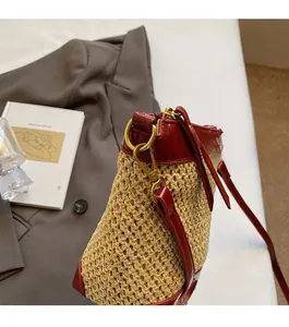 Detail of woven straw crossbody bag with red leather trim and gold hardware on Matisse book