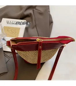 Detailed view of the straw crossbody bag featuring red leather trim and gold hardware