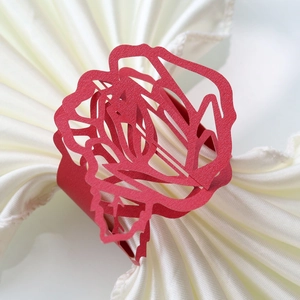 Close-up of red laser-cut paper napkin ring with detailed rose floral pattern