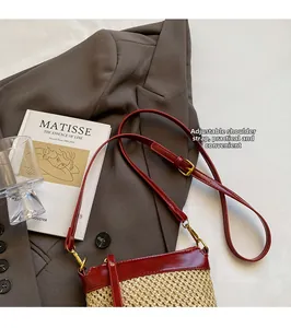 Close-up of woven straw and red leather bag with an adjustable golden metal buckle
