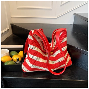 Detail of red and white striped knit tote bag with red leather handles on display