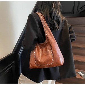 Détail d'un grand sac cabas en cuir marron ciré avec des rivets argentés élégants