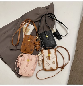 Detail view of four patterned crossbody phone bags with bear prints and matching pendants