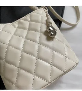 Détail de la texture matelassée blanche avec pendentif cœur argenté sur un sac à bandoulière