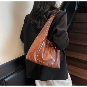 Détail d'un sac cabas marron vintage avec clous argentés et texture cuir vieilli de qualité