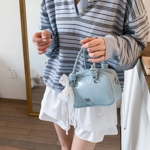 Detail der hellblauen Boston-Tasche mit weißer Spitzenschleife und Perlenanhänger