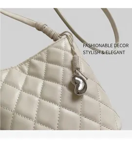 Détail du sac à bandoulière matelassé crème avec breloque en métal et bandoulière nouée