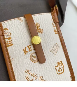 Detail of lychee textured crossbody phone bag with cartoon bear print and gold buckle