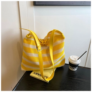 Detail of yellow and white striped woven tote bag with adjustable strap and horn toggle
