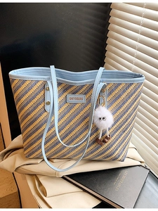 Grand sac cabas tissé à rayures colorées avec pendentif en peluche sur un trench-coat beige