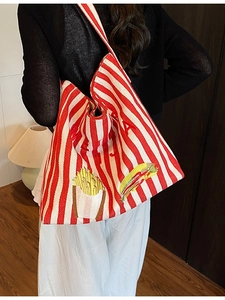 Grand sac cabas en toile rayée avec broderie porté par un mannequin en intérieur