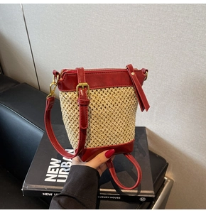 Detail of red leather trim and woven straw texture on a stylish small bucket bag