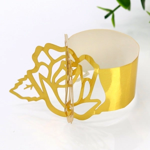 Detailed view of golden laser-cut paper napkin rings with elegant rose flower design