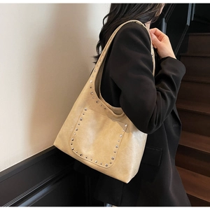 Détail du sac cabas beige avec clous argentés et texture cuir pour un style quotidien