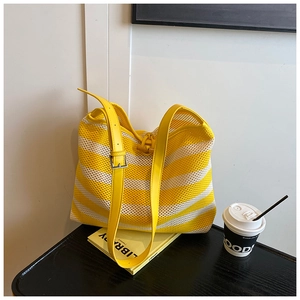 Close-up of yellow and white striped woven tote bag with adjustable leather shoulder strap