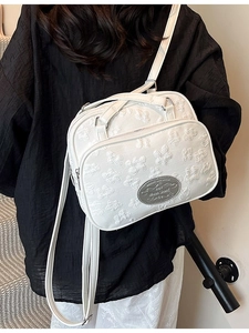 Sac bandoulière blanc à texture florale porté à l'épaule par un mannequin