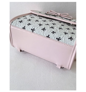 Detail der pink-weißen Handtasche mit Schleifendesign und geprägter Lederstruktur