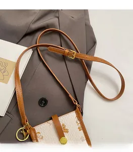 Detail of printed crossbody phone bag with adjustable shoulder strap and gold clasp