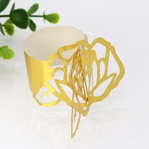 Detailed view of golden laser-cut paper napkin ring with 3D rose pattern for weddings
