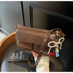 Detail of vintage brown oil wax leather bag with pearl bow and cartoon charm
