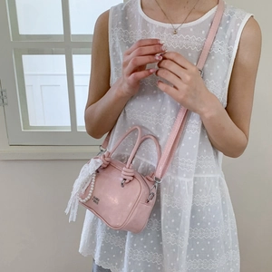 Detail der rosa Mini-Umhängetasche mit Perlenkette und Spitzenbogen am Handgriff